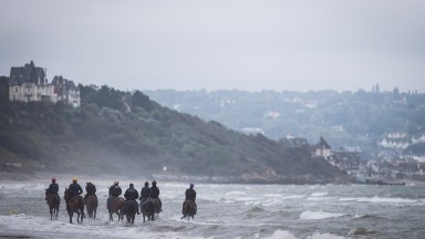 A group of racehorses heading up the beach at Deauville on Monday