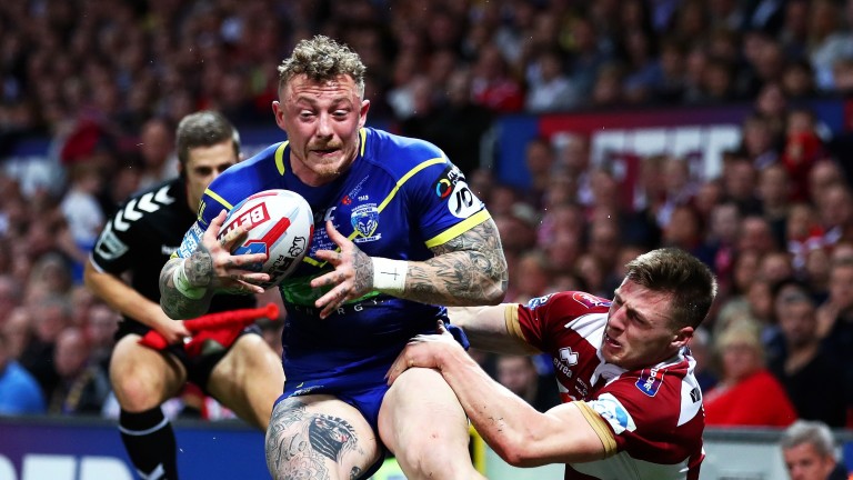 Josh Charnley of Warrington Wolves is tackled by Tom Davies of Wigan Warriors
