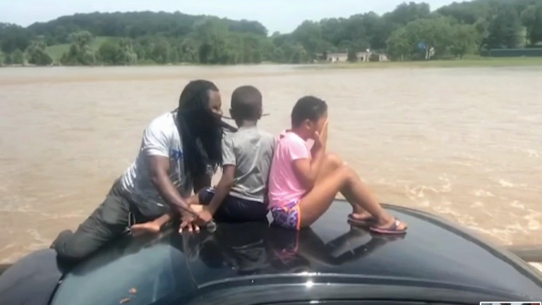 The father moved the children to the roof of the car as the water went over the doors